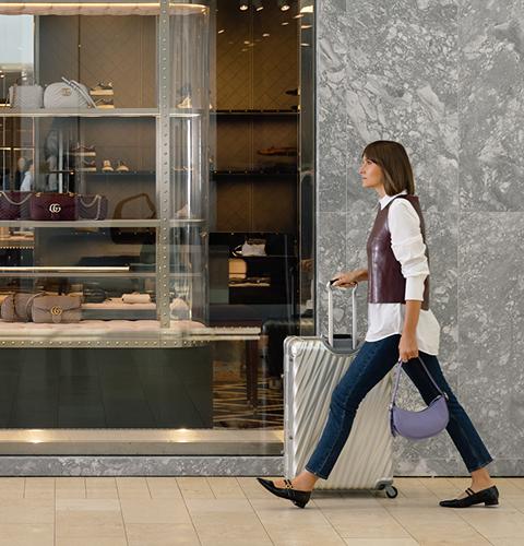 Visitor walking through the shopping centre with luggage and bags near multiple retail stores