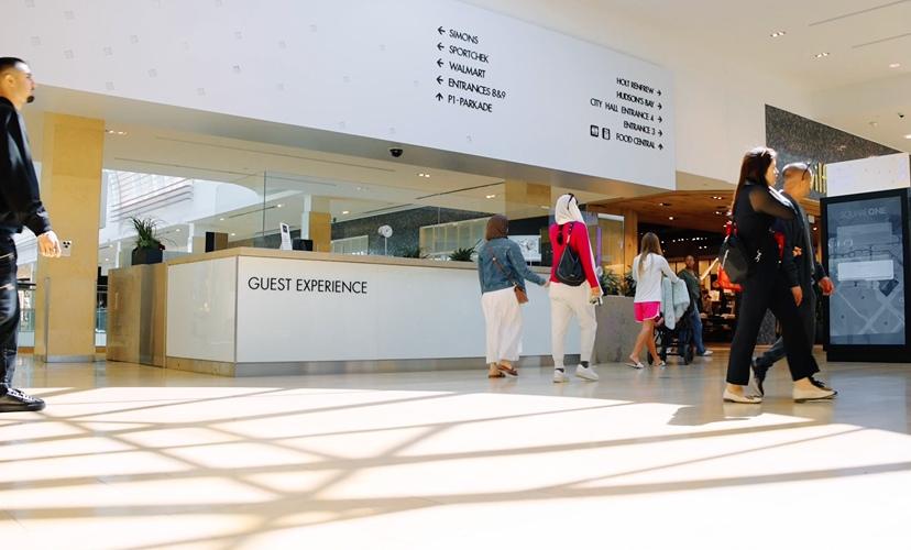 Visitors walking near a guest experience desk with open and accessible pathways inside the mall