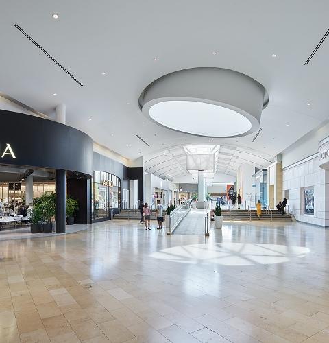 Spacious mall walkway with accessible paths and shoppers moving through popular retail areas