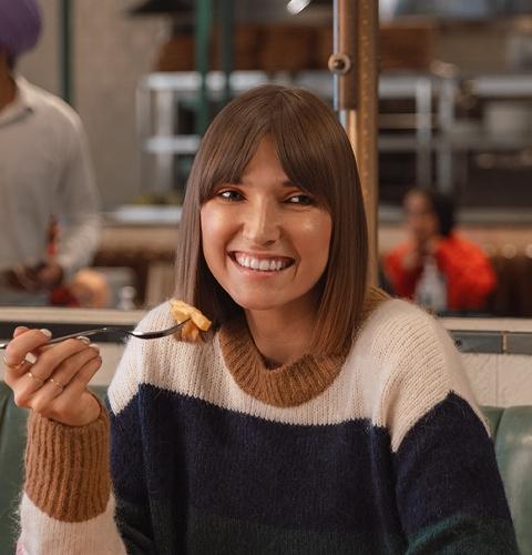 Woman enjoying a meal at a restaurant, highlighting a relaxed and comfortable dining experience
