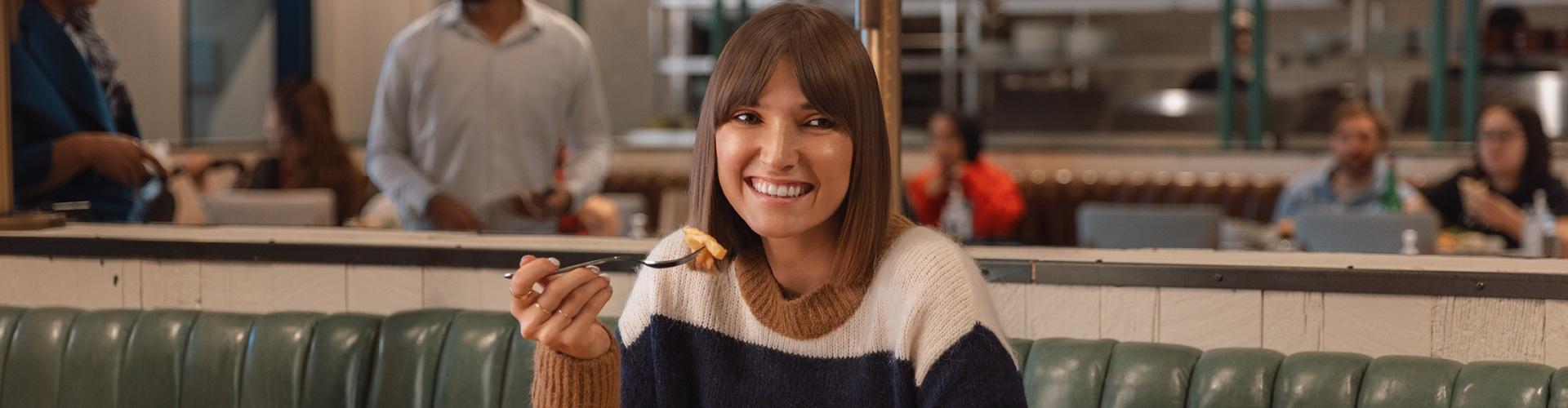 Woman enjoying a meal at a restaurant, highlighting a relaxed and comfortable dining experience