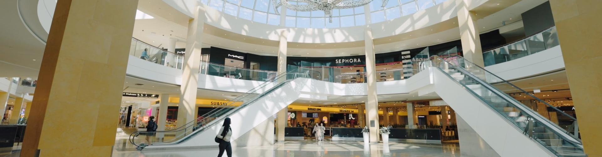 Shopping centre interior featuring escalators and retail stores including Sephora