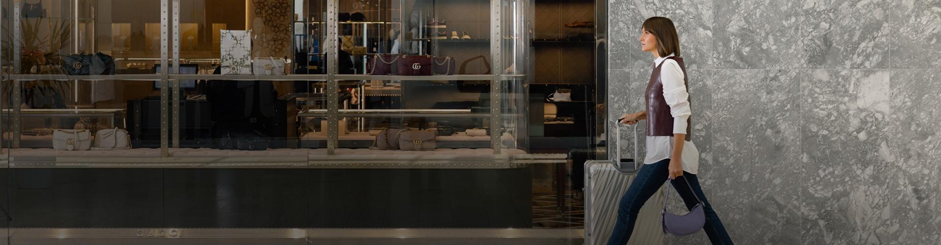 Visitor walking through the shopping centre with luggage and bags near multiple retail stores