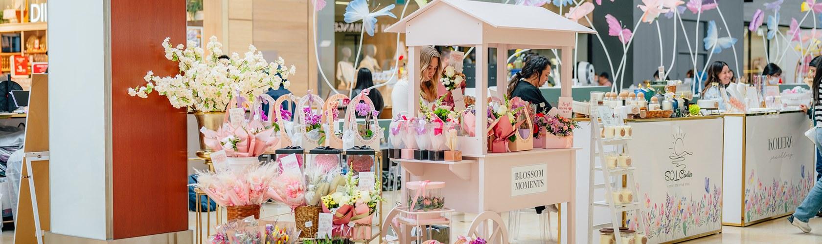 Seasonal market with artisan stalls, floral displays, and curated products in a shopping centre