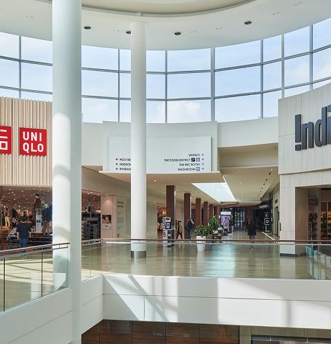 Shoppers exploring stores like Uniqlo and Indigo in a busy and well-designed mall interior